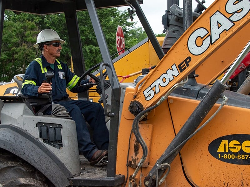 Equipment operator driving a paving machine during asphalt road construction project