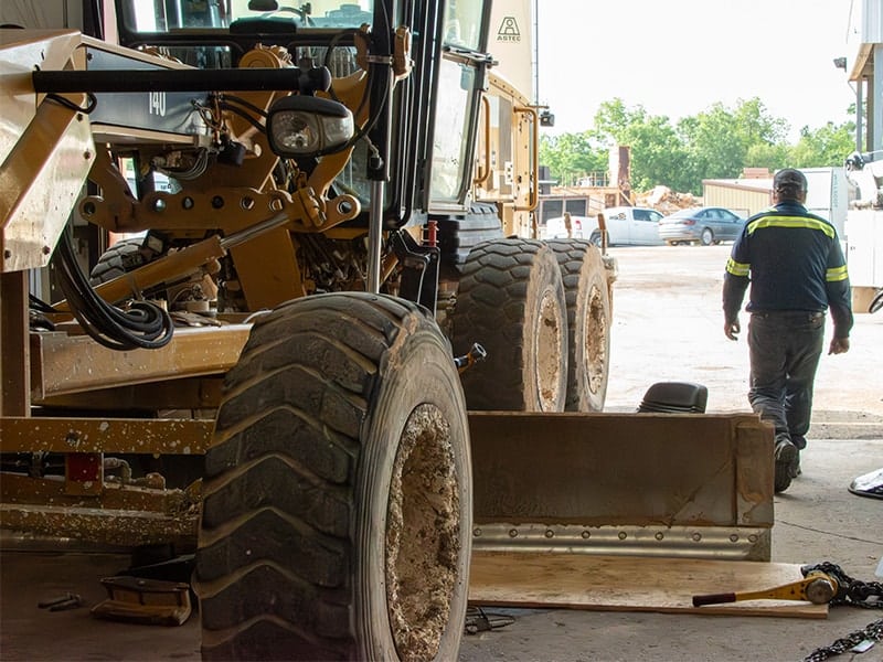 Equipment mechanic servicing a road scraper machine