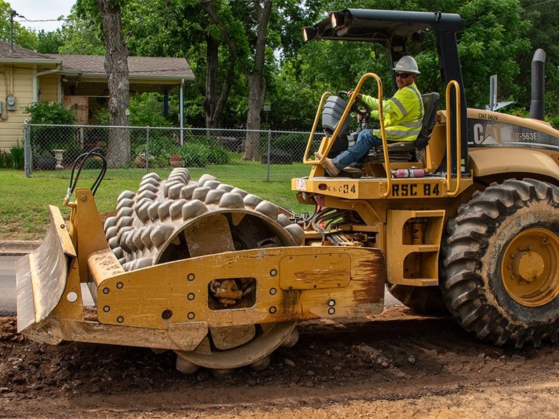 Equipment operator driving a single drum sheepsfoot roller