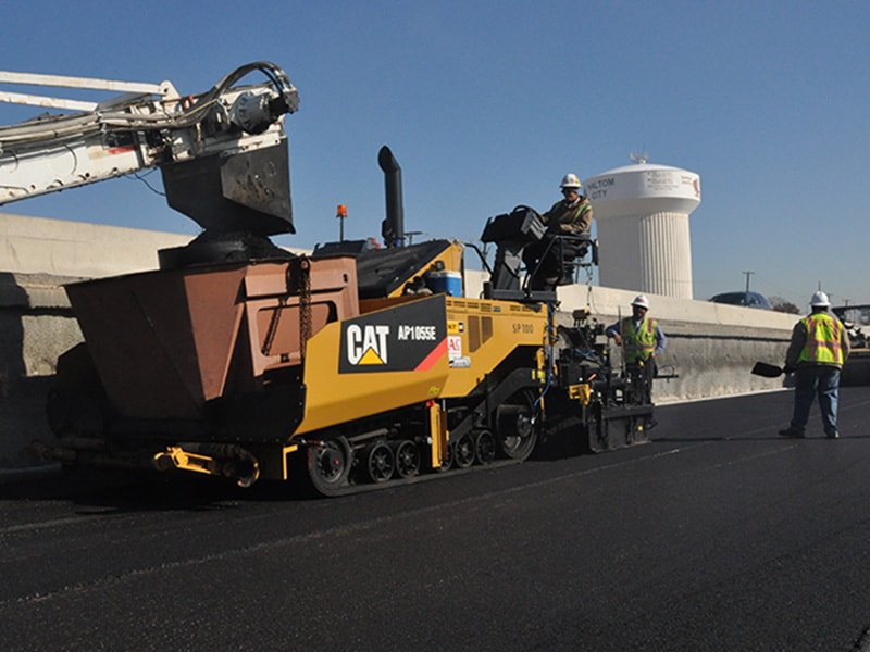 Asphalt paving machine and field personnel during road paving project