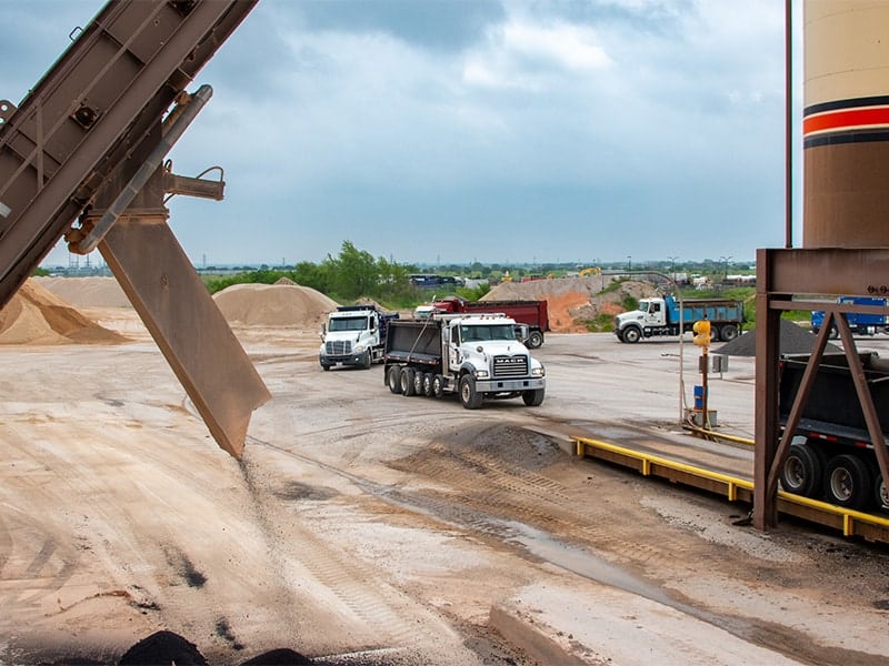 Line of asphalt trucks waiting to pickup asphalt at plant in Saginaw, TX